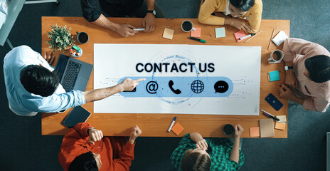 A diverse group of professionals gathers around a table, engaging in a strategic discussion about communication. Various contact icons feature prominently on the design. Trope