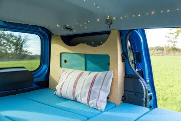 gemütlicher Minicamper steht im Grünen mit Stühlen davor 