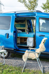 gemütlicher Minicamper steht im Grünen mit Stühlen davor 