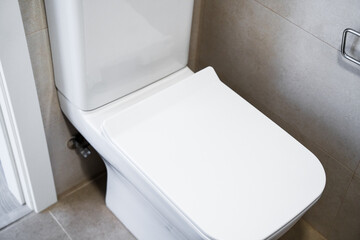 Side view of modern white toilet with clean ceramic surfaces in bright minimalist bathroom
