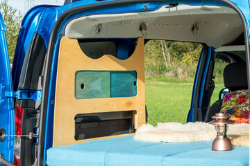 gemütlicher Minicamper steht im Grünen mit Stühlen davor 