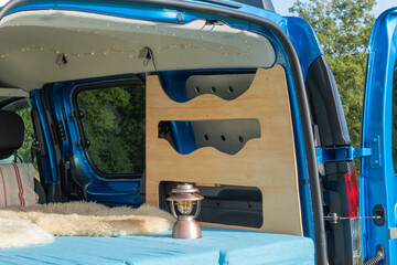 gemütlicher Minicamper steht im Grünen mit Stühlen davor 