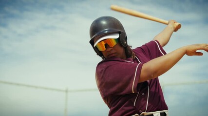 A focused female batter in a helmet and sunglasses takes a powerful practice swing with a wooden bat at the plate, ready to hit a home run on the field. - Powered by Adobe