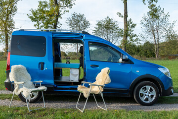 gemütlicher Minicamper steht im Grünen mit Stühlen davor 