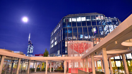 Modern office building in city center illuminated at night. Rows of lit windows against the architectural grid of a modern facade. Concrete and glass facade in its night version.