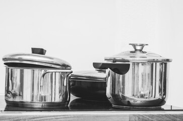 Stainless steel pots and pans on a modern black glass cooktop