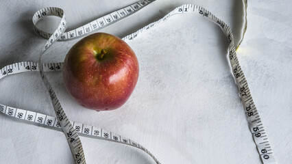 Red Apple and Measuring Tape on White Background. Concept for Diet, Weight Loss, Healthy Eating and Wellness.