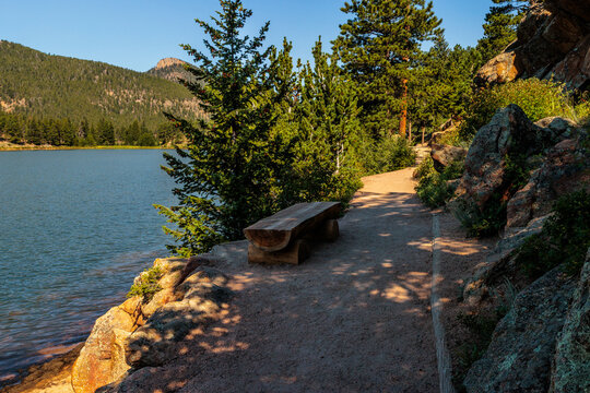 A shaded log bench along the trail around Lily Lake within Rocky Mountain National Park, Colorado