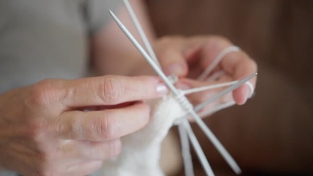 crafting warm socks, elderly artisan knitting with care, closeup of skilled hands weaving soft yarn into sock, an elderly craftsman carefully knitting white sock using doublepointed needles