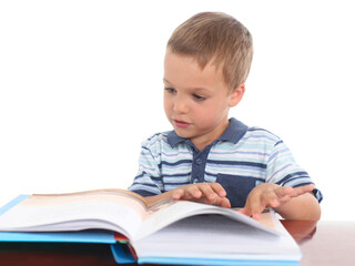 Preschool-age little boy reading a book on a white background, showing focus and curiosity.
