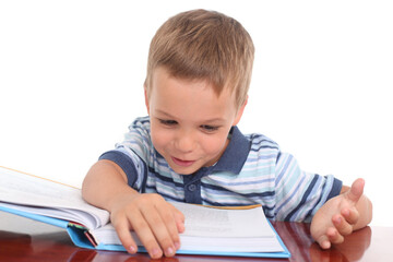 Preschool-age little boy reading a book on a white background, showing focus and curiosity.