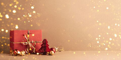Red paper Christmas trees, gifts, and decorations on beige background with bokeh, minimalist design