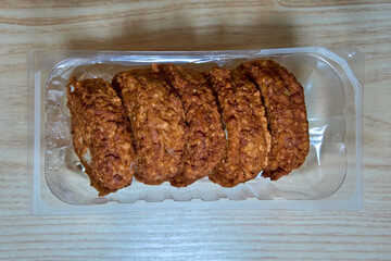 Pork cutlets in a plastic tray, arranged in rows on a wooden surface.