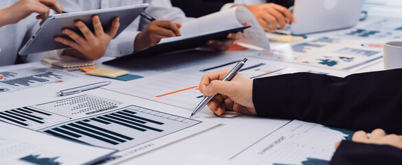 A productive business meeting featuring professionals collaborating with digital devices and analyzing financial charts in a modern office setting for effective strategy development. SACTR