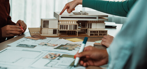A collaborative design session featuring a scale model of a modern building, architectural...