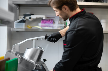 Chef slicing vegetables using industrial slicer in kitchen