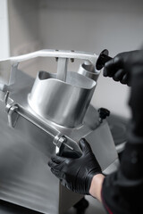 Unrecognizable chef slicing vegetables using industrial slicer in kitchen