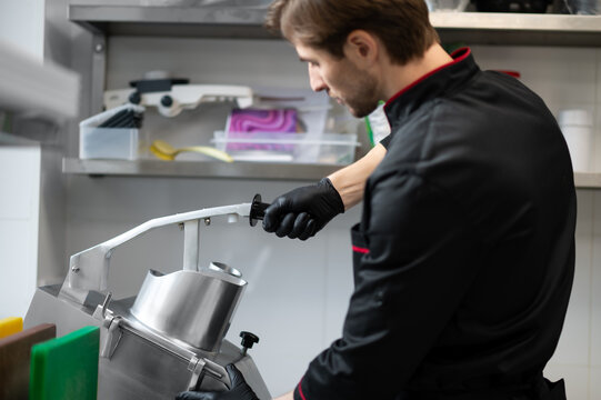 Chef slicing vegetables using industrial slicer in kitchen