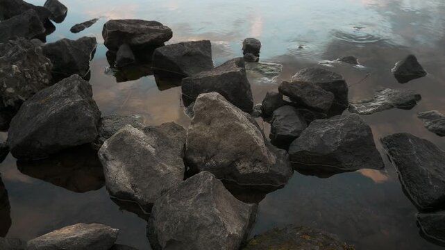 鏡面の水面とゴツゴツした岩のある晩秋の湖畔