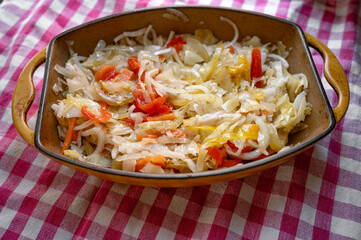 Fermented or pickled cabbage served in a ceramic dish on checkered textile background