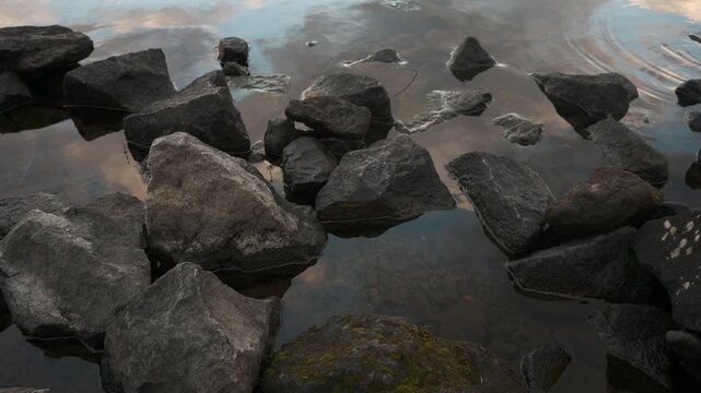 鏡面の水面とゴツゴツした岩のある晩秋の湖畔