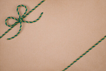 Green and Gold Christmas String Tied in Bow on Kraft Paper Background