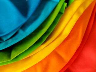 A collection of colorful, deflated balloons is arranged on a textured white surface. 