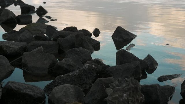 鏡面の水面とゴツゴツした岩のある晩秋の湖畔