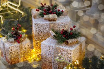 Elegant Christmas gift boxes with golden glitter, decorated with red berries and fir branches