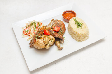 Poulet braisé avec attiéké sur assiette blanche et set tissé africain. Cuisine africaine traditionnelle. Traiteur africain.