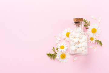 Fresh chamomiles with medicines on color background, top view