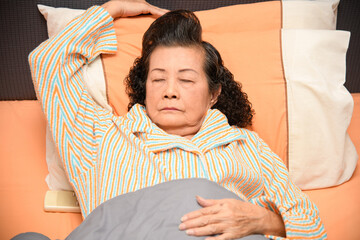 An old woman is sleeping on the bed