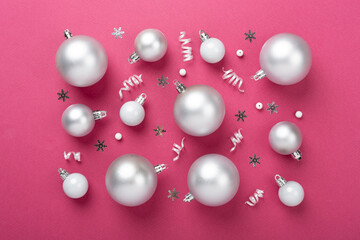 Grey Christmas balls with decor on color background, top view