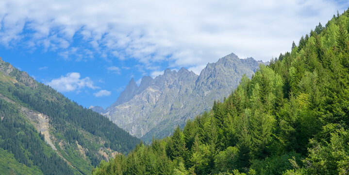 Scenic Svaneti landscape featuring rugged mountains covered with dense forests under natural light.