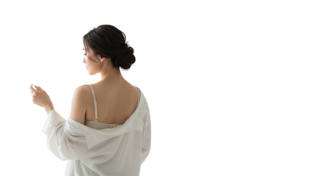 A young woman with dark hair styled up, seen from behind, wearing a white shirt off her shoulders and a bra strap, looking over her shoulder, isolated on transparent background
