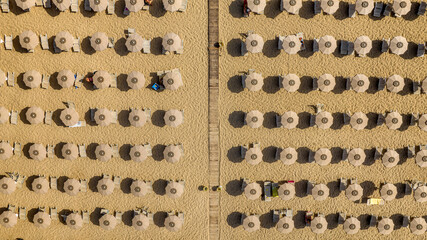 Aerial view of a beach resort with many umbrellas on a sandy beach. An Italian beach club for summer vacations.