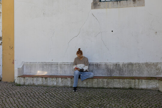 Young woman sitting on bench using smartphone - Powered by Adobe