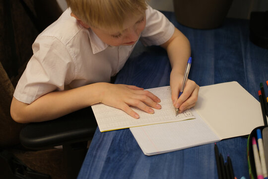 Child writing in notebook practicing shapes for school education