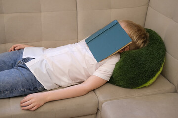 Tired child sleeping on sofa after reading book