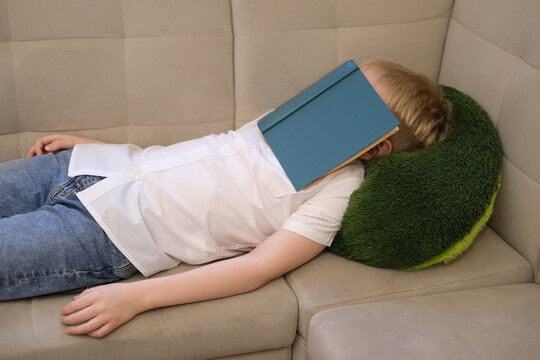 Tired child sleeping on sofa after reading book