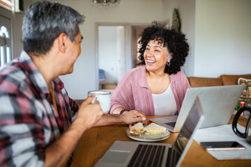 Mature couple laughing over coffee while working at home