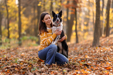 Woman walking her cute dog in autumn park