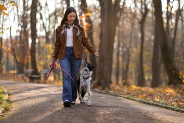 Obraz premium Woman walking her cute dog in autumn park, space for text
