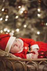 Little girl lays on a holiday background in Santa costume