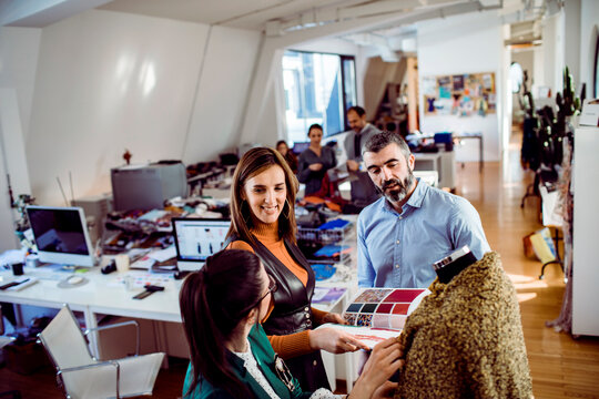 Smiling adults collaborating on fashion design in creative studio - Powered by Adobe