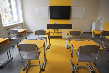 Stylish classroom with desks, chairs and tv at school