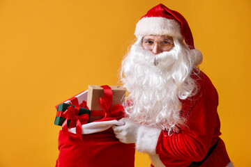 Santa Claus with bag full of gifts on yellow background, space for text. Merry Christmas and Happy New Year