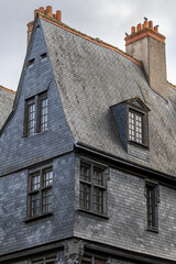Historic building facade covered with black slate tiles stands on Place Plumereau in Tours France creating a unique medieval city architecture landscape view under the cloudy sky outdoors