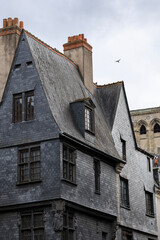 Naklejka premium Historic building facade covered with black slate tiles stands on Place Plumereau in Tours France creating a unique medieval city architecture landscape view under the cloudy sky outdoors