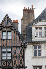 Historic half-timbered house with wooden beams and red brick stands next to a white stone building with slate roof in Tours France creating a beautiful medieval city architecture view outdoors